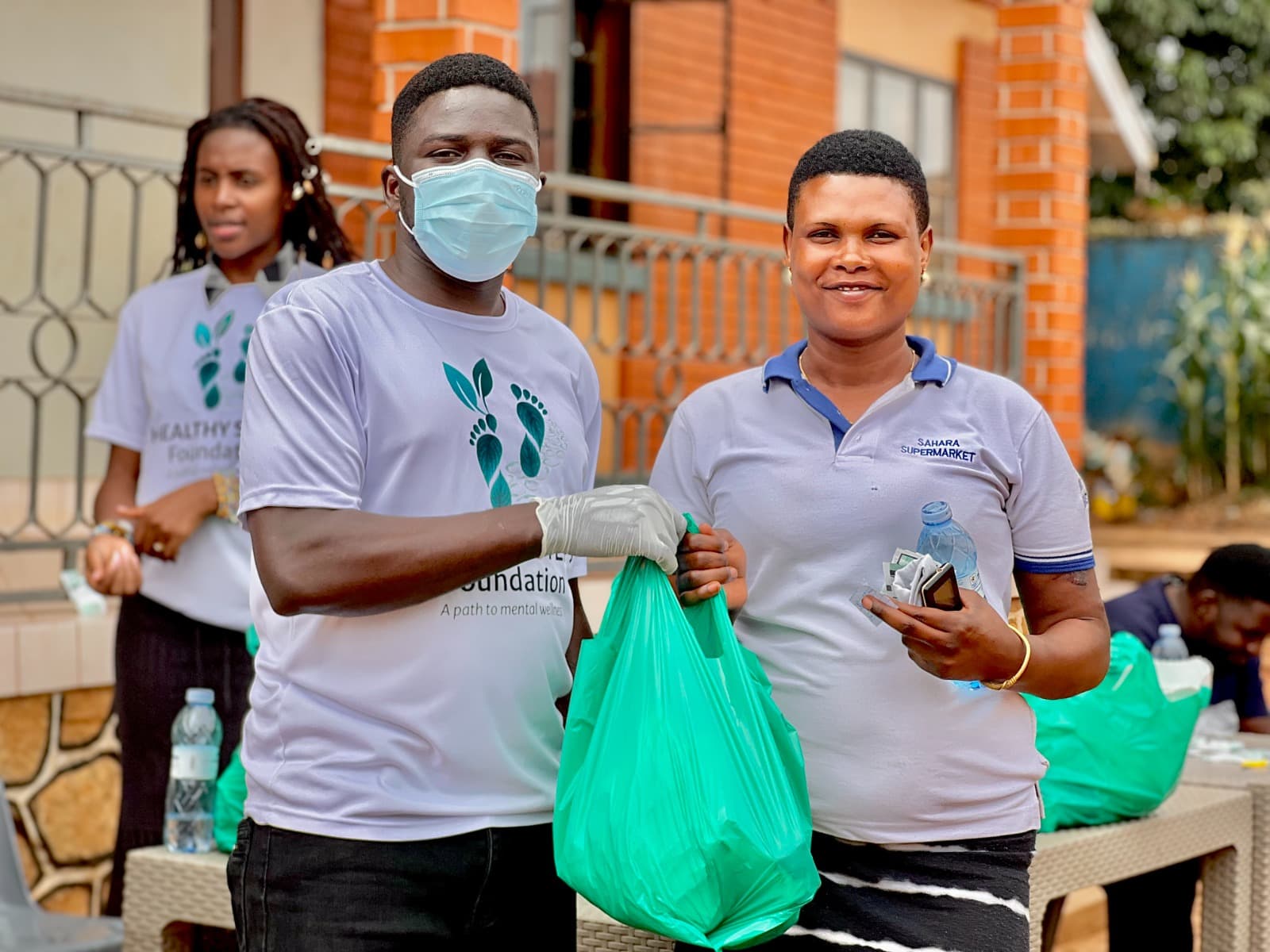 A Healthy Steps Foundation volunteer handing a food relief bag to a community member in Wakiso, Uganda